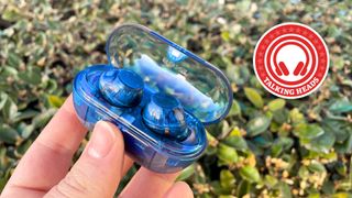 Sony WF-C710N wireless earbuds in fromt of a green bush with Talking Heads roundel