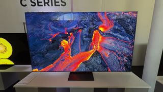 TCL C8K TV on a white media unit with nature shots on screen