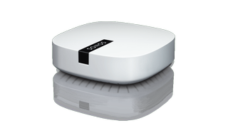 A white Sonos Boost on a white background, shot at a 3/4 angle, with its reflection below it.